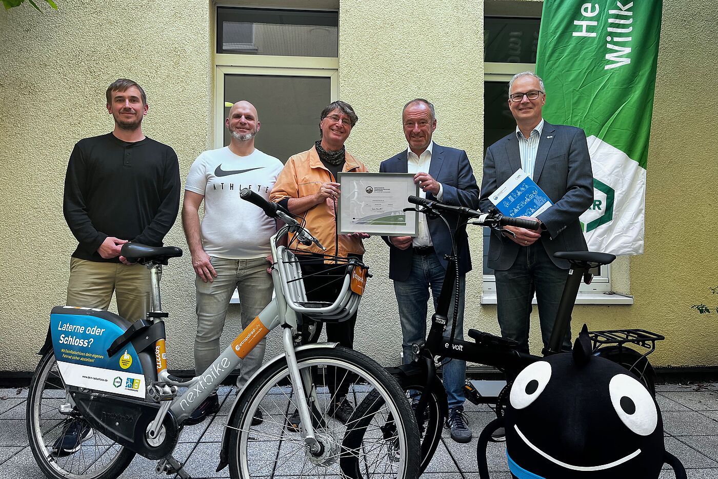 v.l. Jan Gade und Stefan Oppermann (VRR Radverkehrskoordinatoren), Andreas K. Bittner (ADFC Projekt "Fahrradfreundlicher Arbeitgeber"), Oliver Wittke (VRR Vorstandssprecher) und Marc Zietan (ADFC NRW Landesvorstand) – im Vordergrund ein Metropolrad und rechts das Maskottchen der Europäischen Mobilitätswoche.