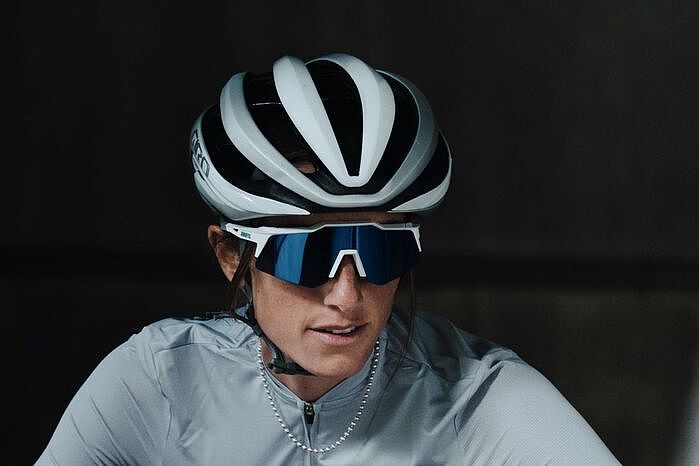 Portraitbild einer Frau mit weißem Fahrradhelm und der Speedcraft XS-Brille des Herstellers 100%. 